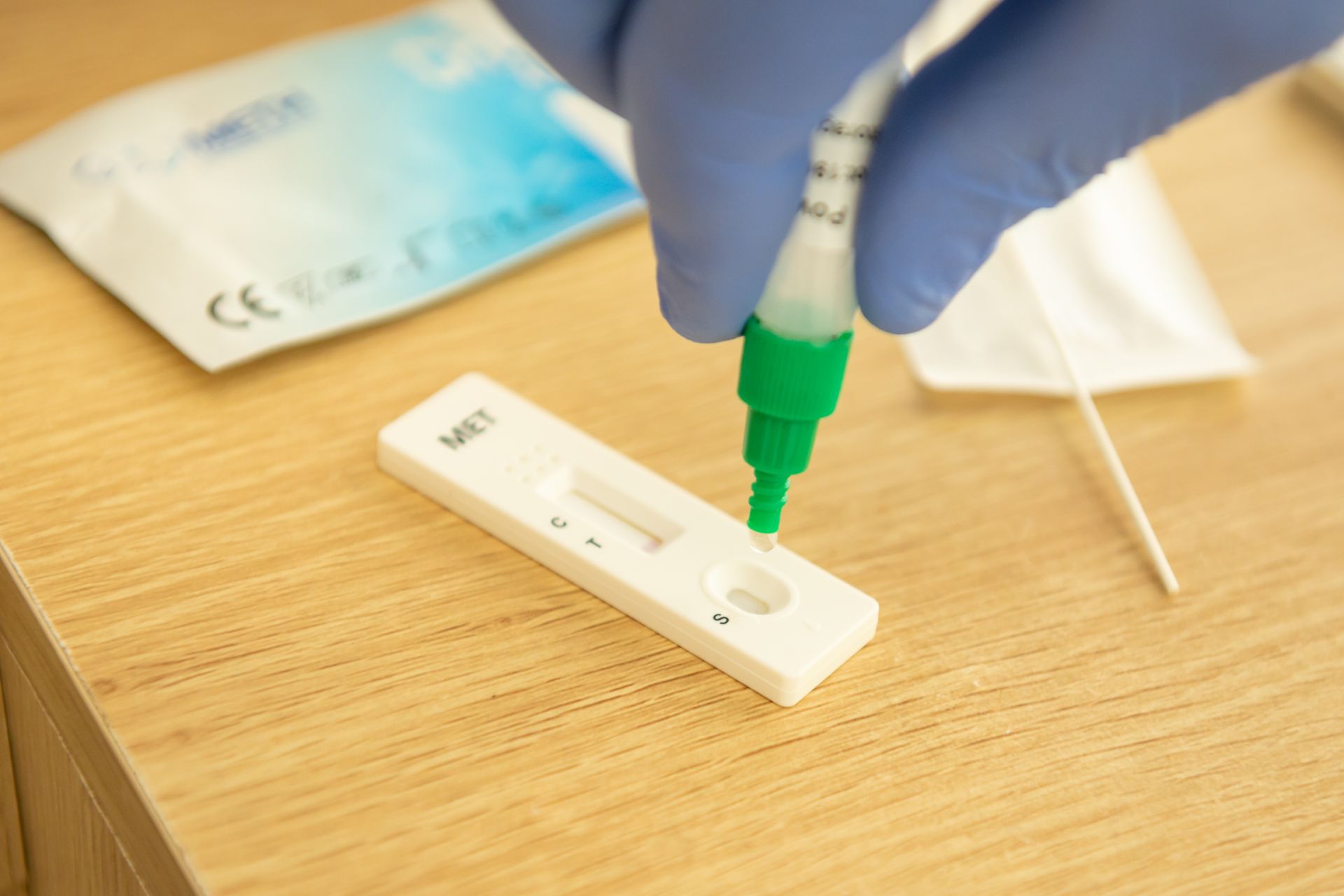 A person is taking a sample from a test kit on a wooden table.