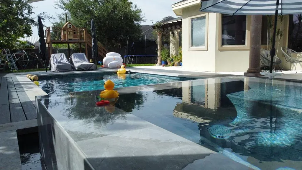Backyard swimming pool with a yellow duck float and lounge chairs by the water