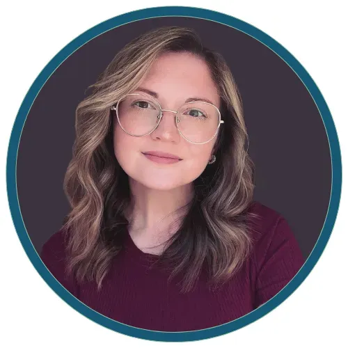 Headshot of a woman with glasses and wavy hair on a dark background with a teal circular border