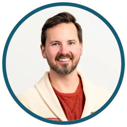 Smiling man in a white sweater and red shirt inside a teal circular frame