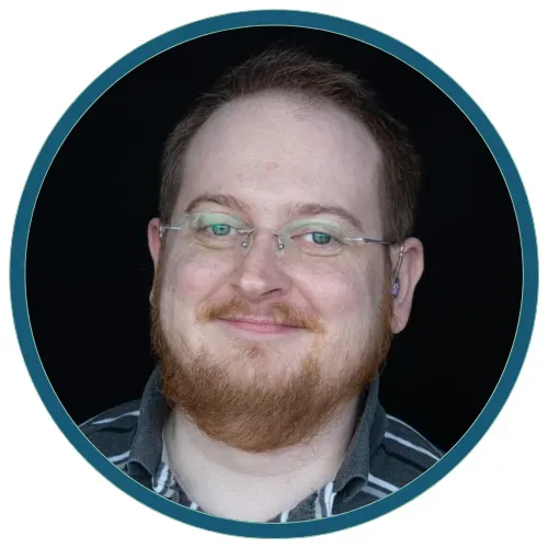 Smiling man with glasses and red beard in a teal circular frame
