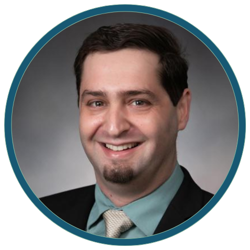 Smiling man in a suit and tie against a gray background, framed by a teal circular border