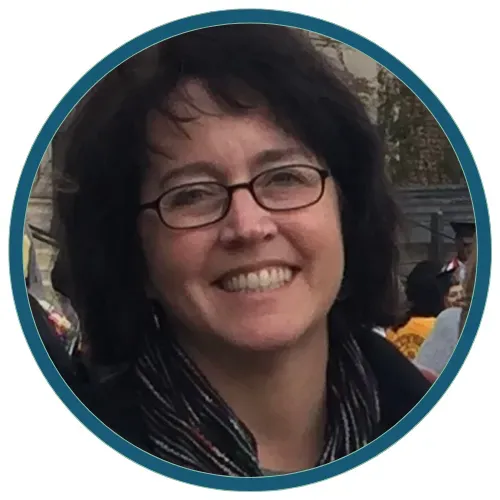 Smiling woman with glasses and dark hair, wearing a scarf, in a circular profile photo with teal border