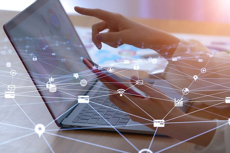 Person using laptop and smartphone, connected by a network of digital icons.