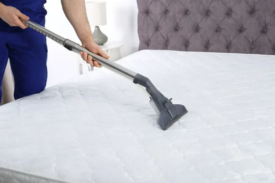 Person Vacuuming a White Mattress — Phil Lindfield's Big Red Carpet Cleaning In Tallwoods Village, NSW