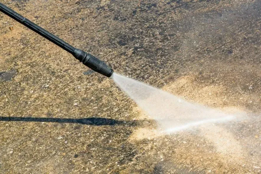 Pressure Washer Spraying Water Onto a Concrete Surface — Phil Lindfield's Big Red Carpet Cleaning In Taree, NSW