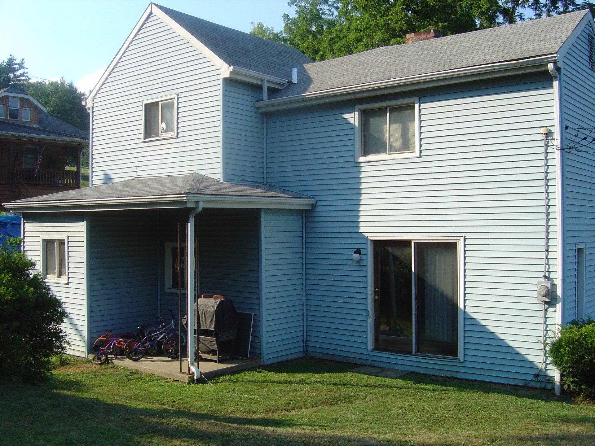 The back of a house with a grill on the porch