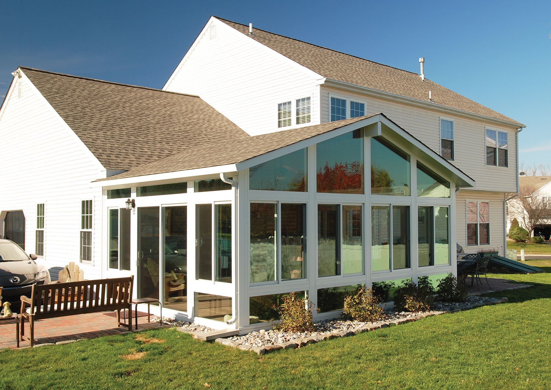 Go To Four Season Sunrooms a white house with a large sunroom on the side