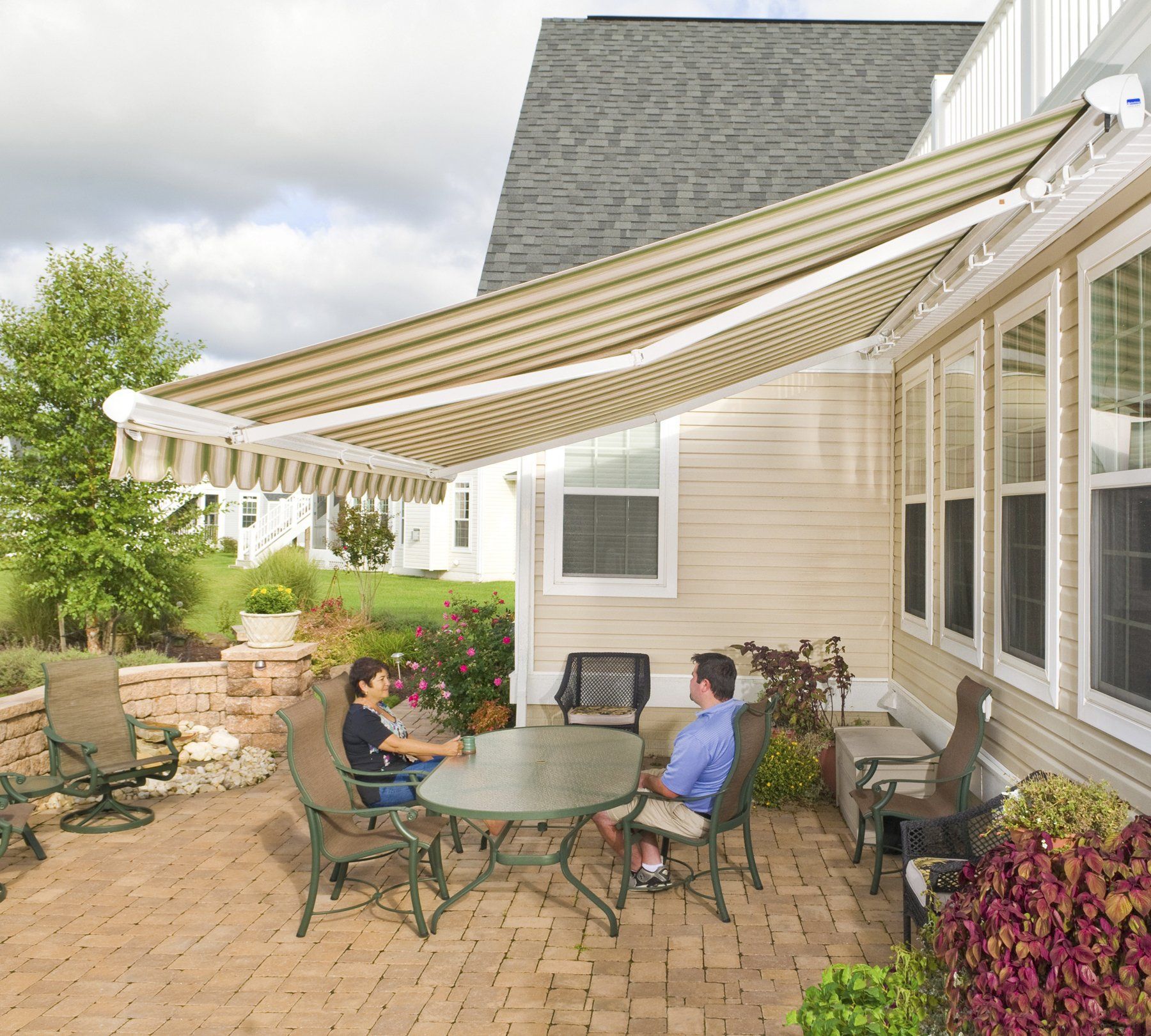 A man and woman sit under an awning on a patio
