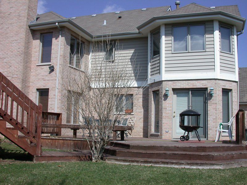 A large brick house with a wooden deck and stairs