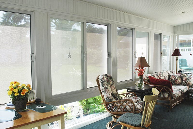 A living room with a lot of windows and chairs