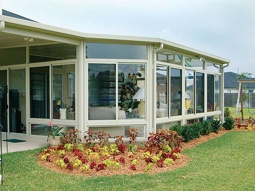 a sunroom with a lot of windows and flowers in front of it