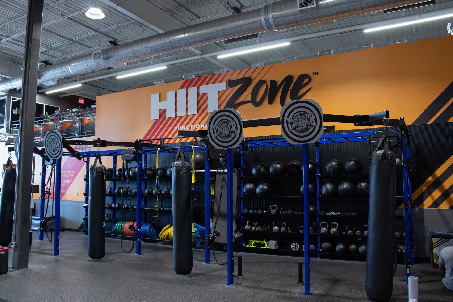 Gym interior with equipment, including weights and punching bags, labeled "HIIT Zone".