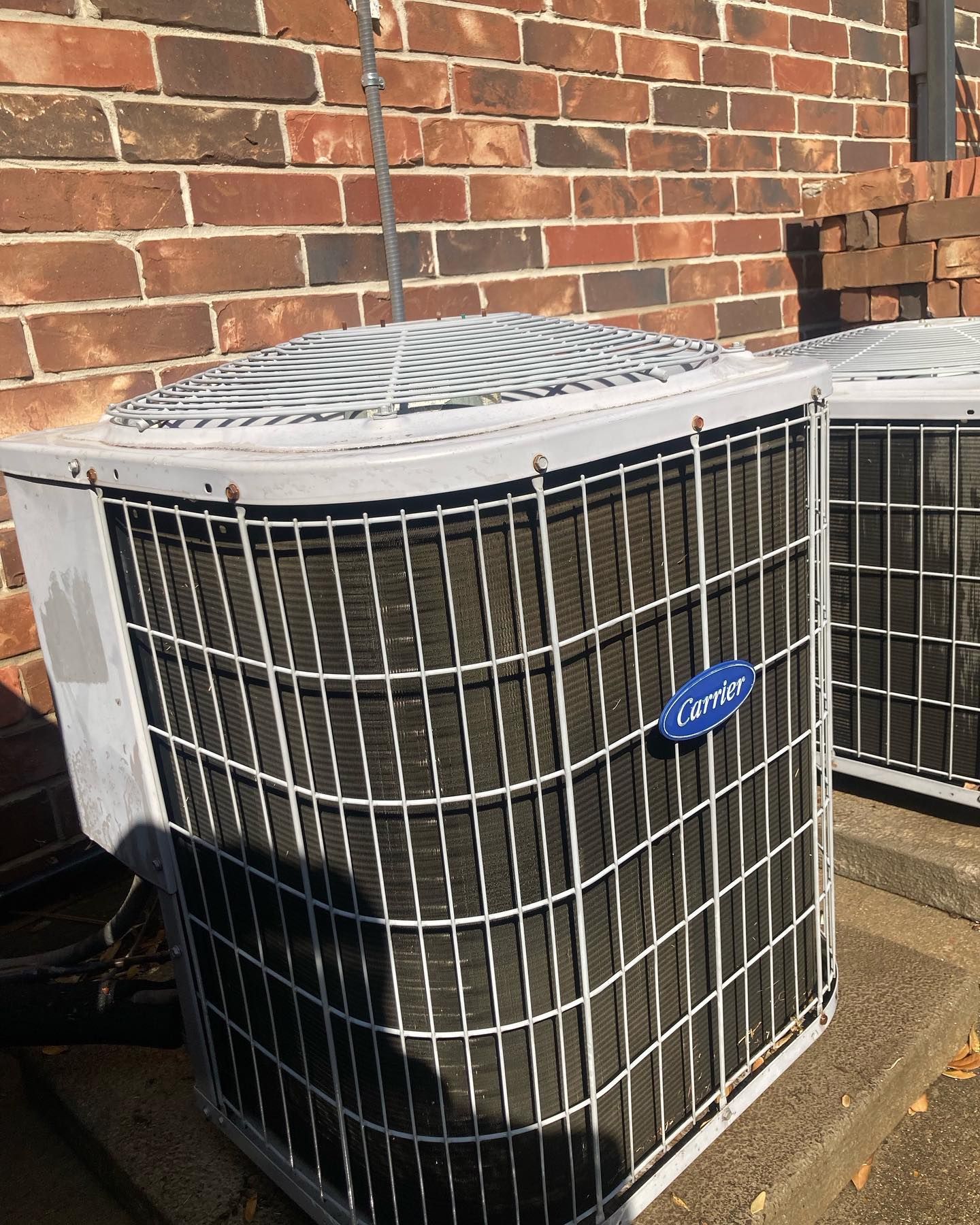 Two air conditioners are sitting on the side of a brick building.