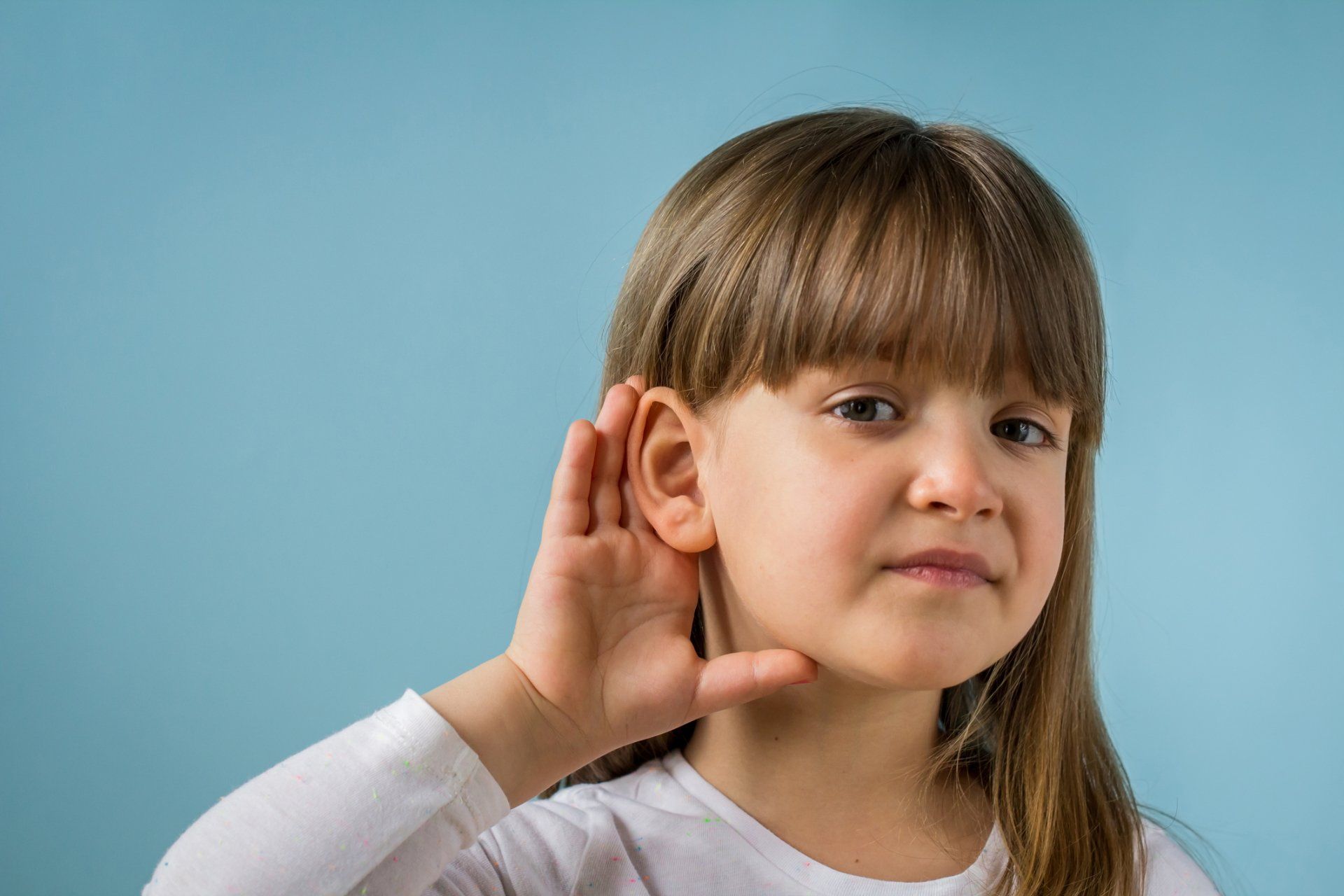 A kid cupping her ear to hear better