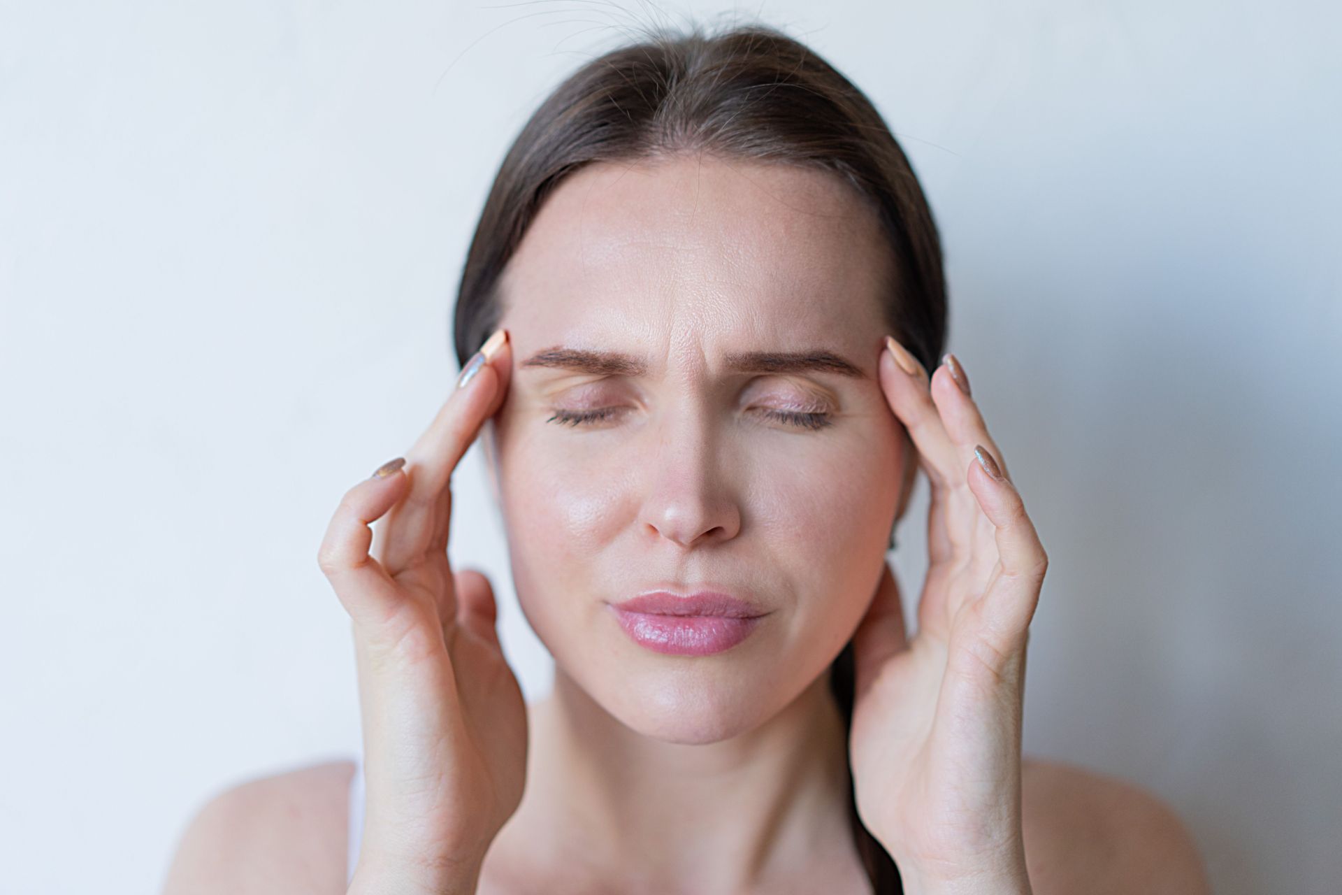 Woman with eyes closed pressing her temples, suffering migraine
