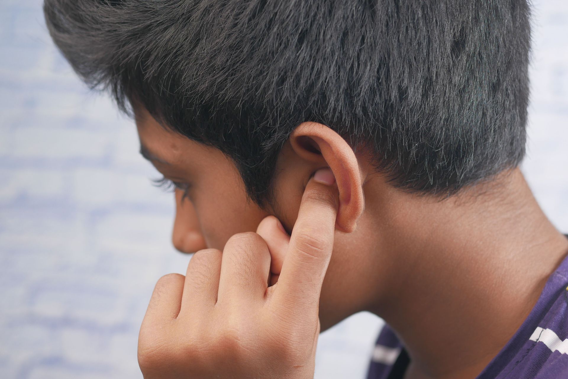 Side view of a person touching their ear due to middle ear infection