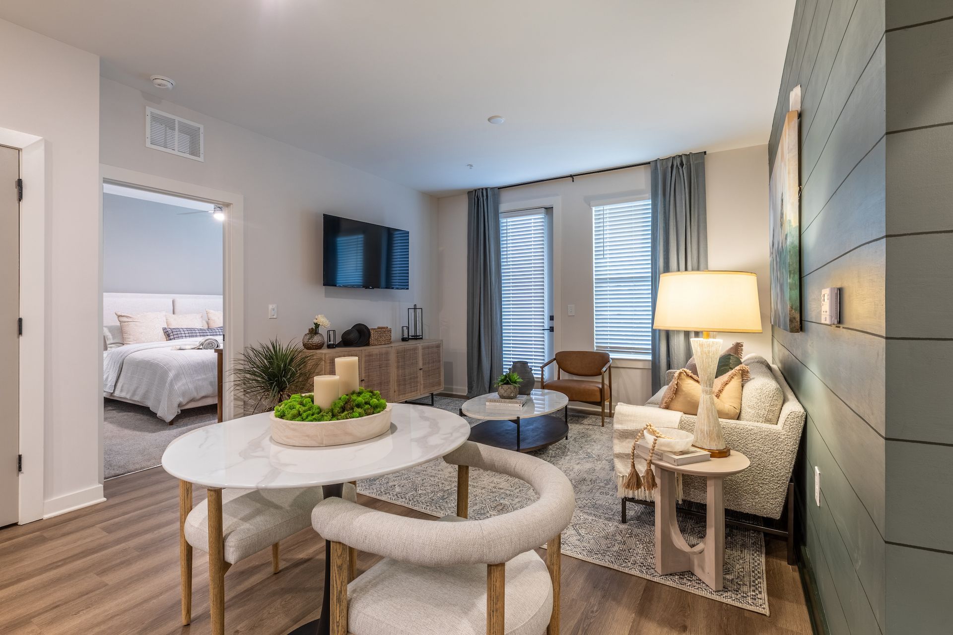 Modern apartment living room with open layout, wood floors, and neutral color palette.