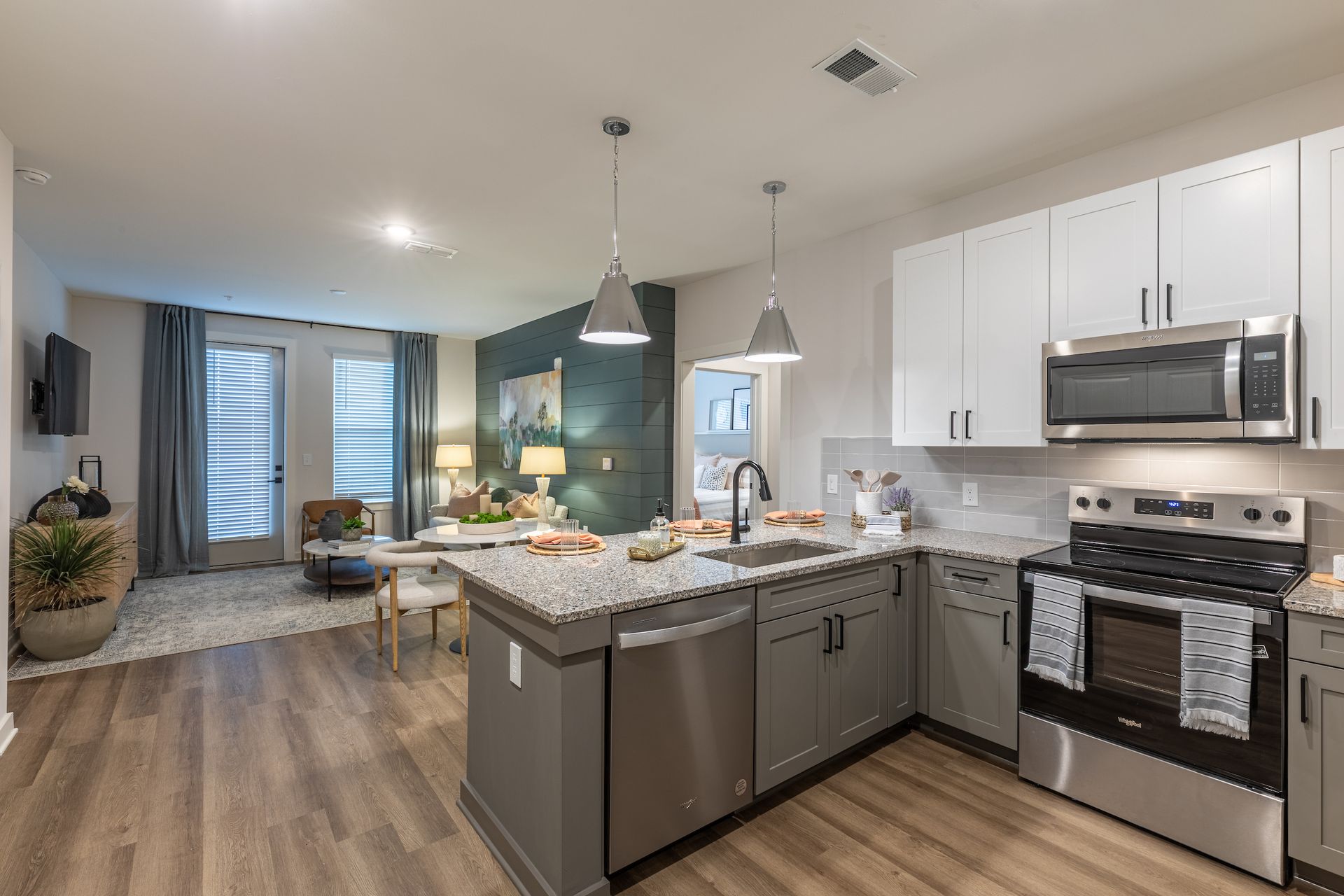Modern kitchen with island, stainless steel appliances, and adjacent living area with natural light.