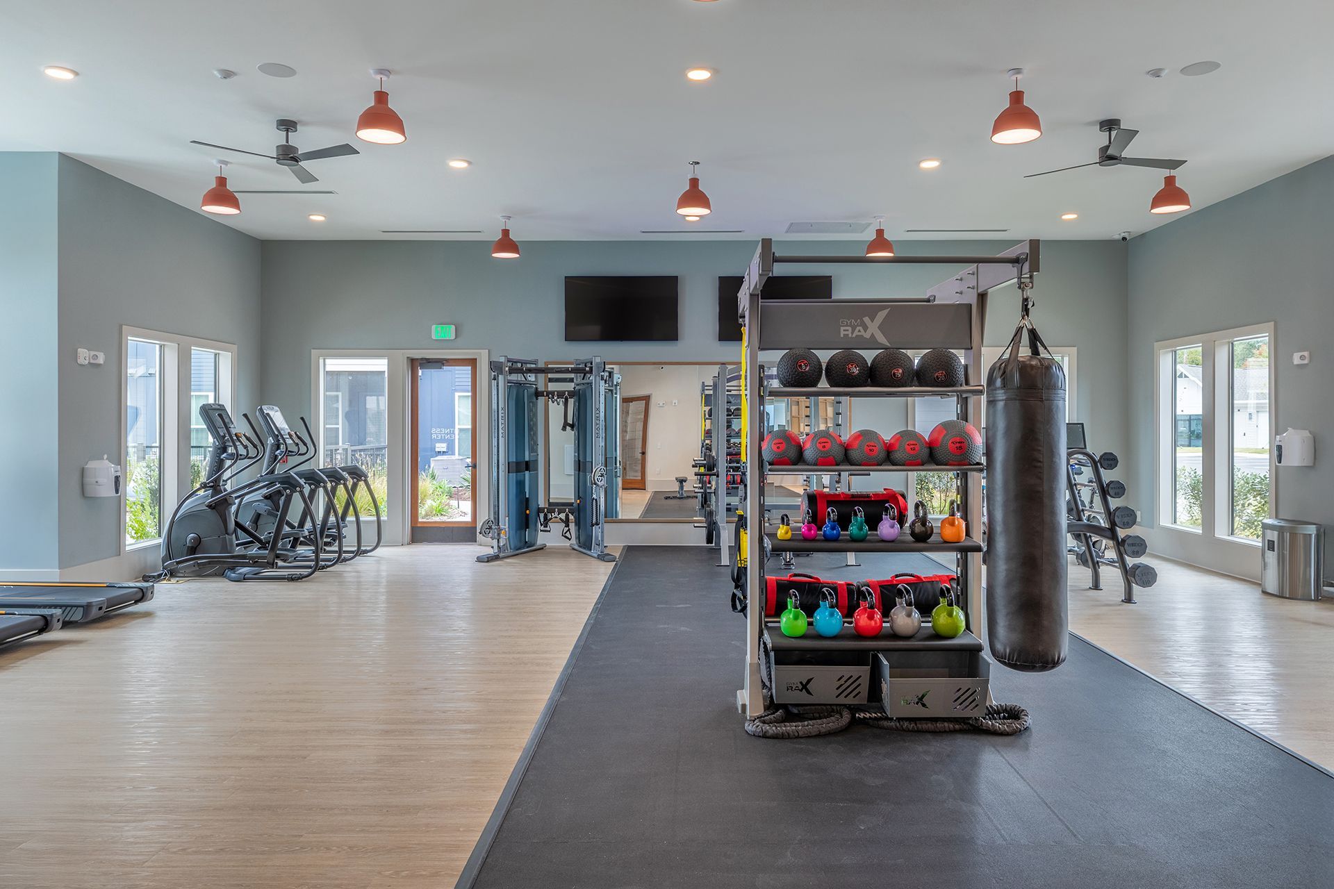 Bright gym interior with cardio machines, weights, and hanging punching bags