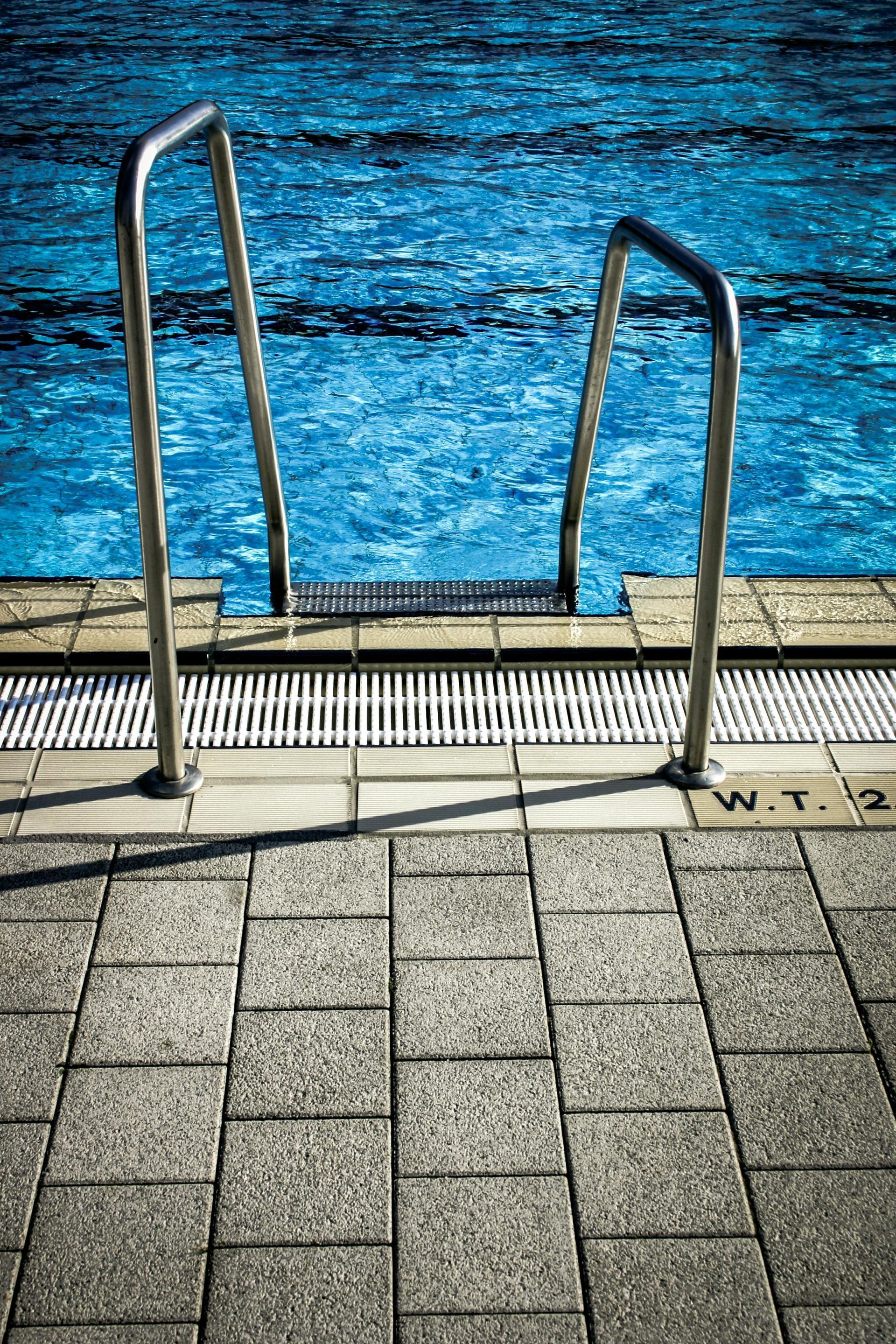 Two little girls wearing sunglasses are swimming in a pool.