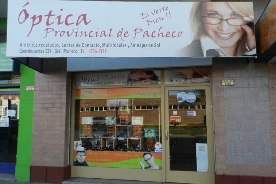Fachada de una óptica con un letrero que dice “Óptica Provincial de Pacheco” y gafas expuestas en el escaparate.