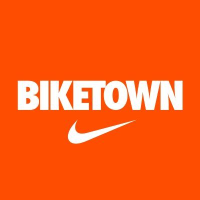 A logo for biketown with a white nike swoosh on an orange background