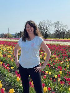 A woman is standing in a field of flowers.