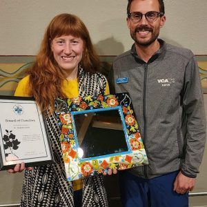 A man and a woman are holding a picture frame and a certificate.