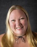 A woman with long blonde hair is smiling and wearing a choker.
