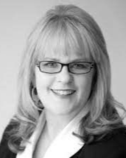 A black and white photo of a woman wearing glasses and smiling.
