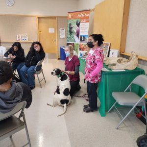 A group of people are sitting around a table with a dog.