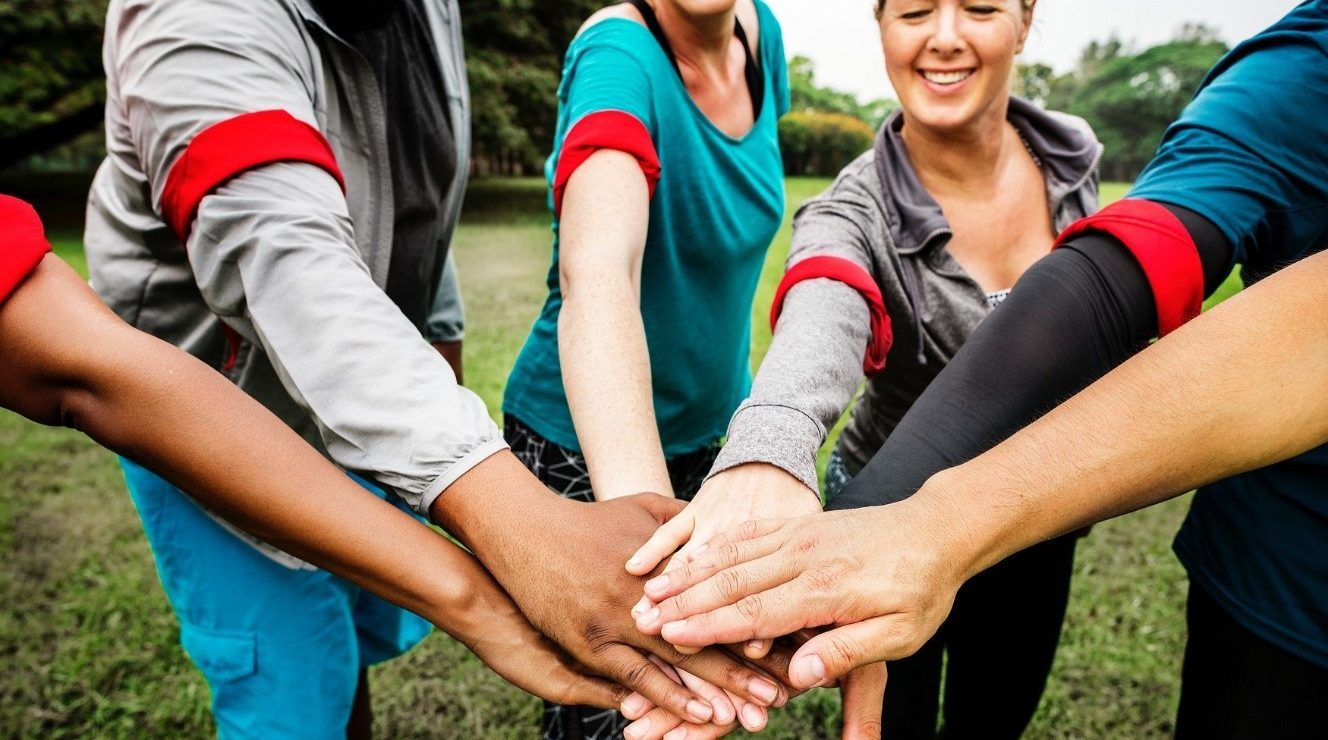 A group of people are putting their hands together in a circle.