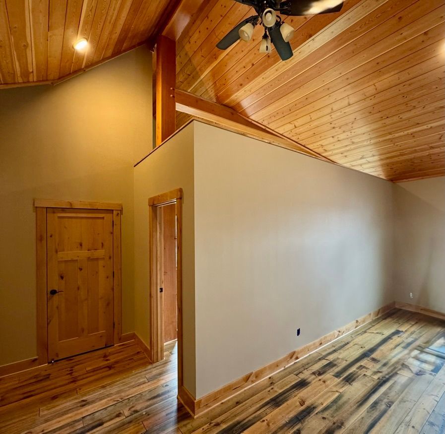Room with wooden floors and ceiling, tan walls, and two doors.