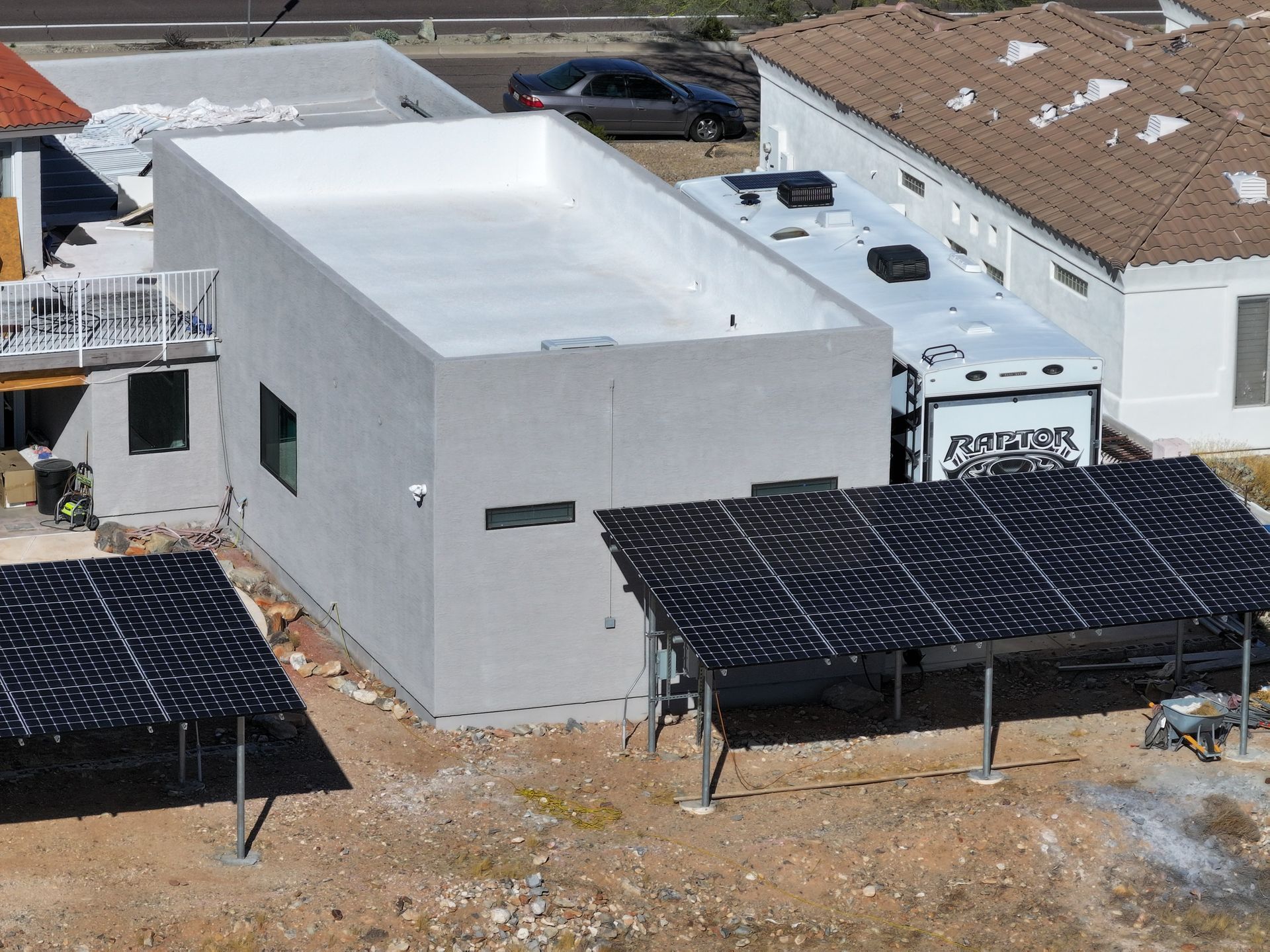 Modern house with flat roof, solar panels, and RV parked next to it.