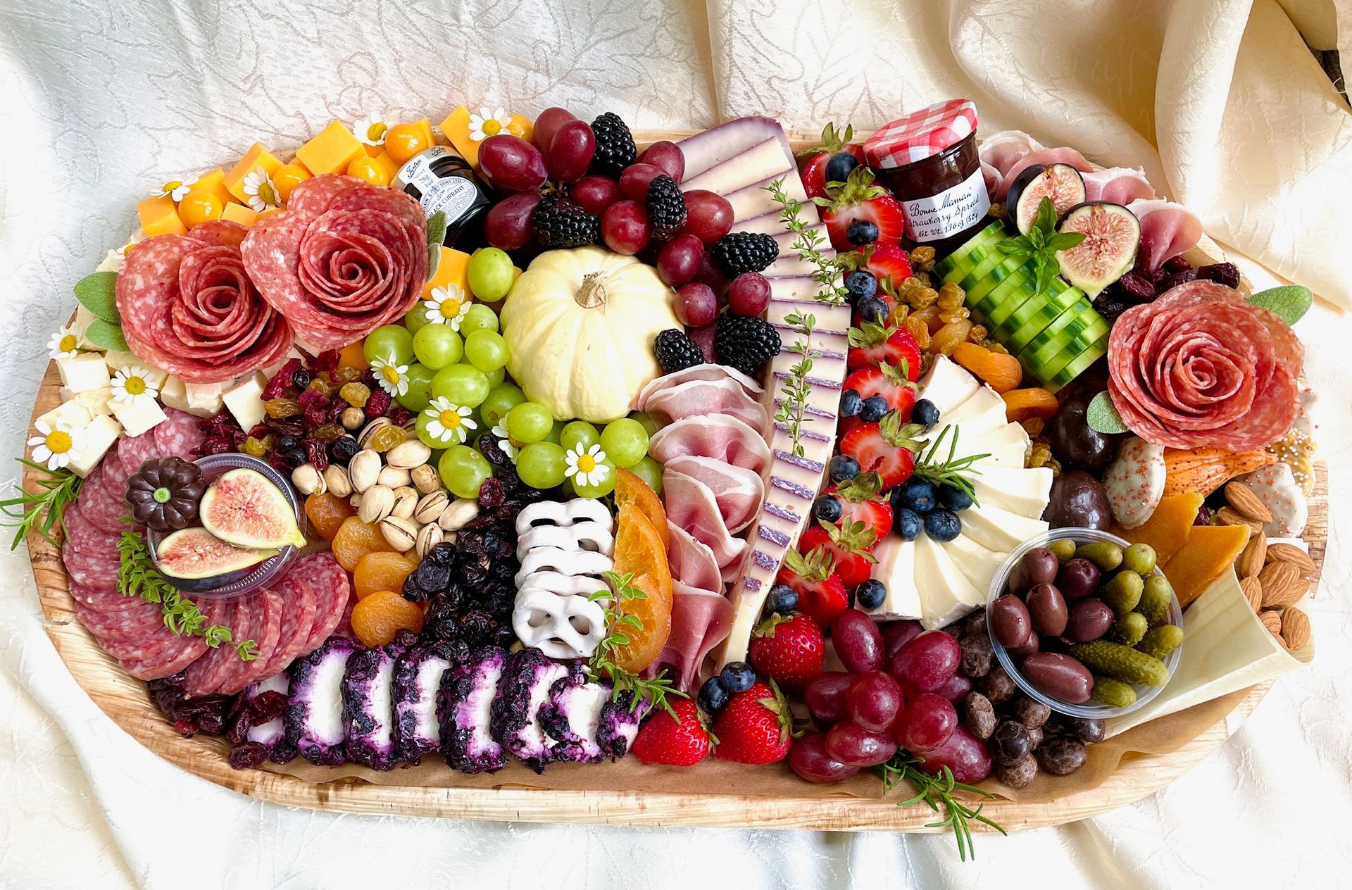 Charcuterie board with varied cheeses, fruits, and meats arranged on a wooden platter.