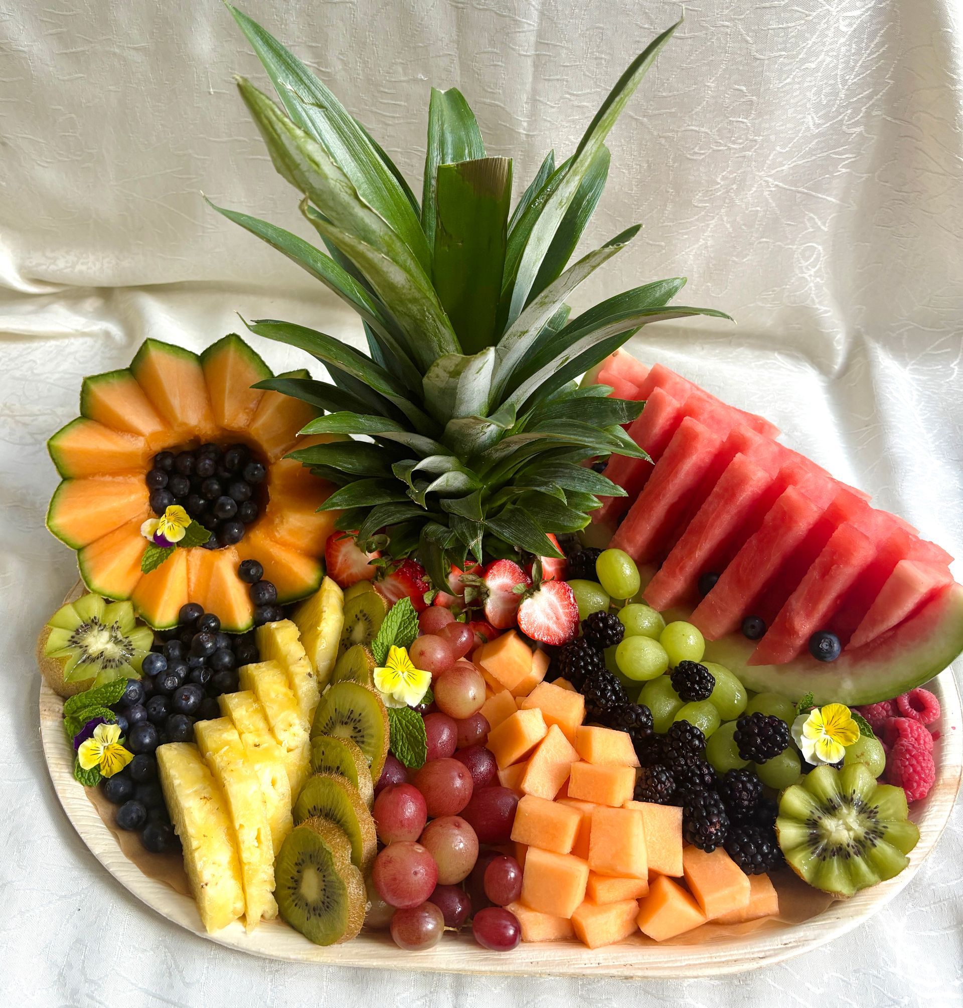 Fruit platter with pineapple, watermelon, cantaloupe, grapes, berries, and kiwi.