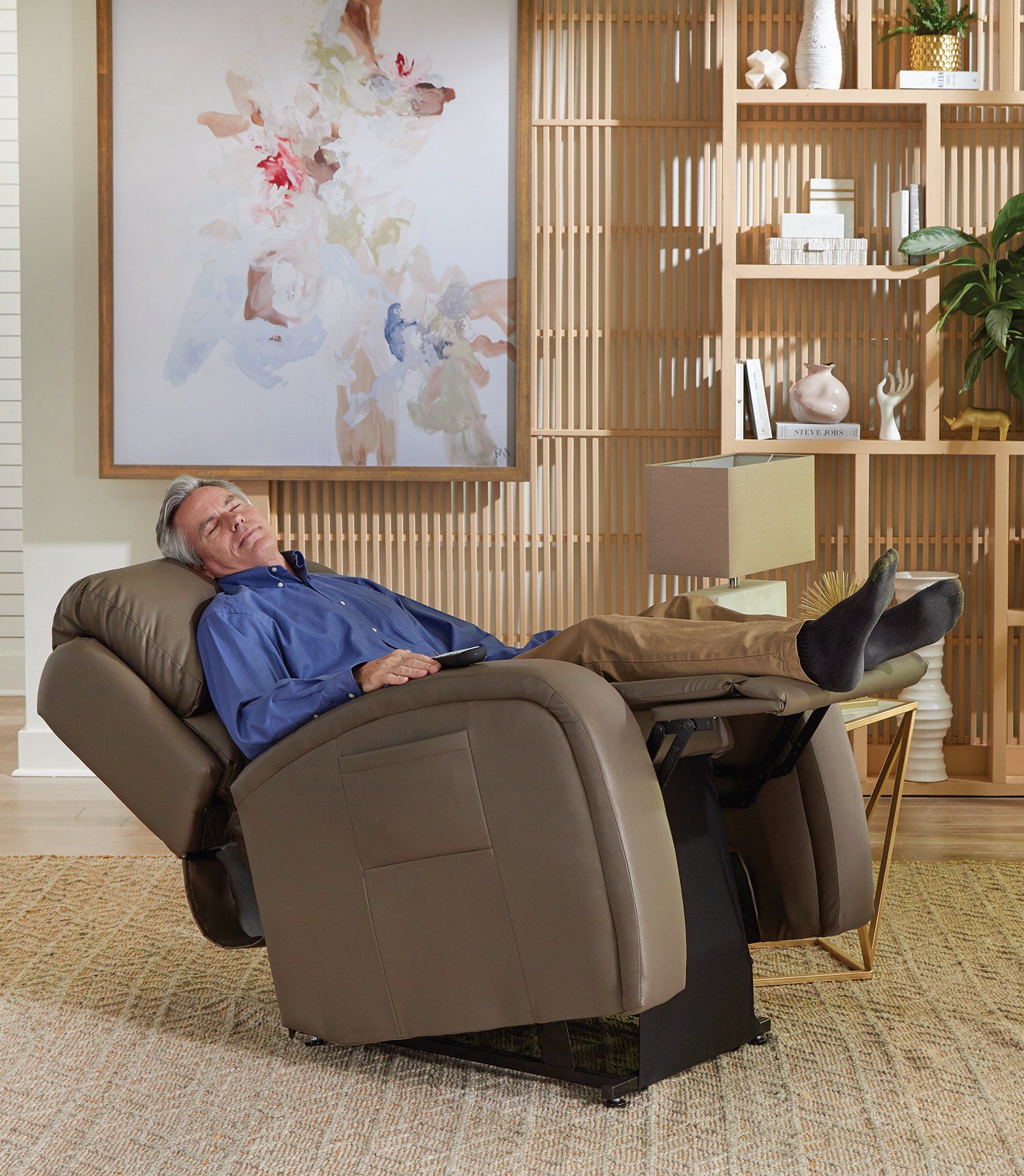 A man is laying in a recliner in a living room.