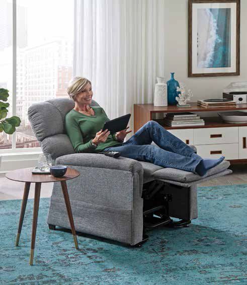 A woman is sitting in a recliner using a tablet computer.