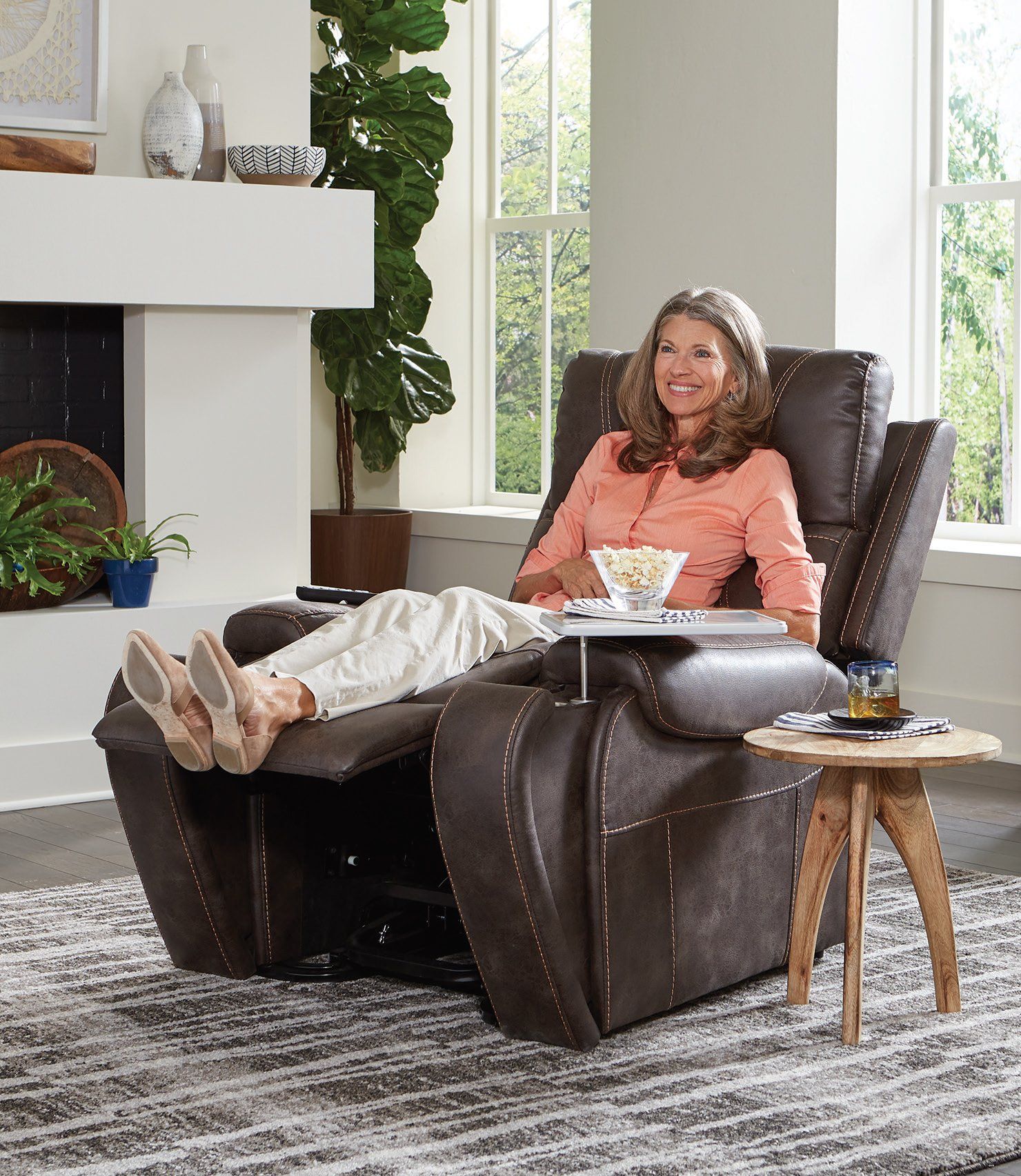 A woman is sitting in a recliner in a living room.