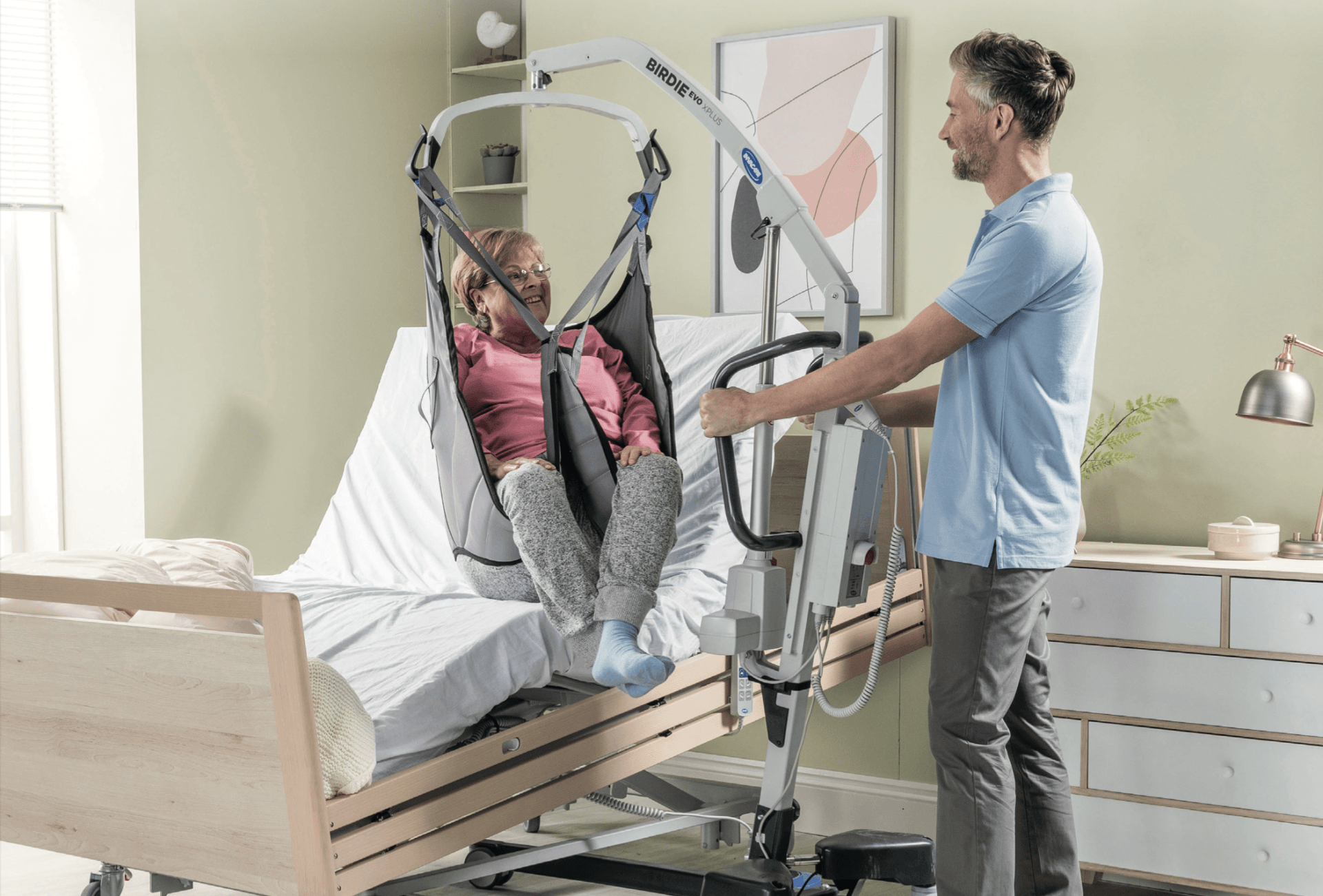 A man is helping a woman in a hospital bed with a lift.
