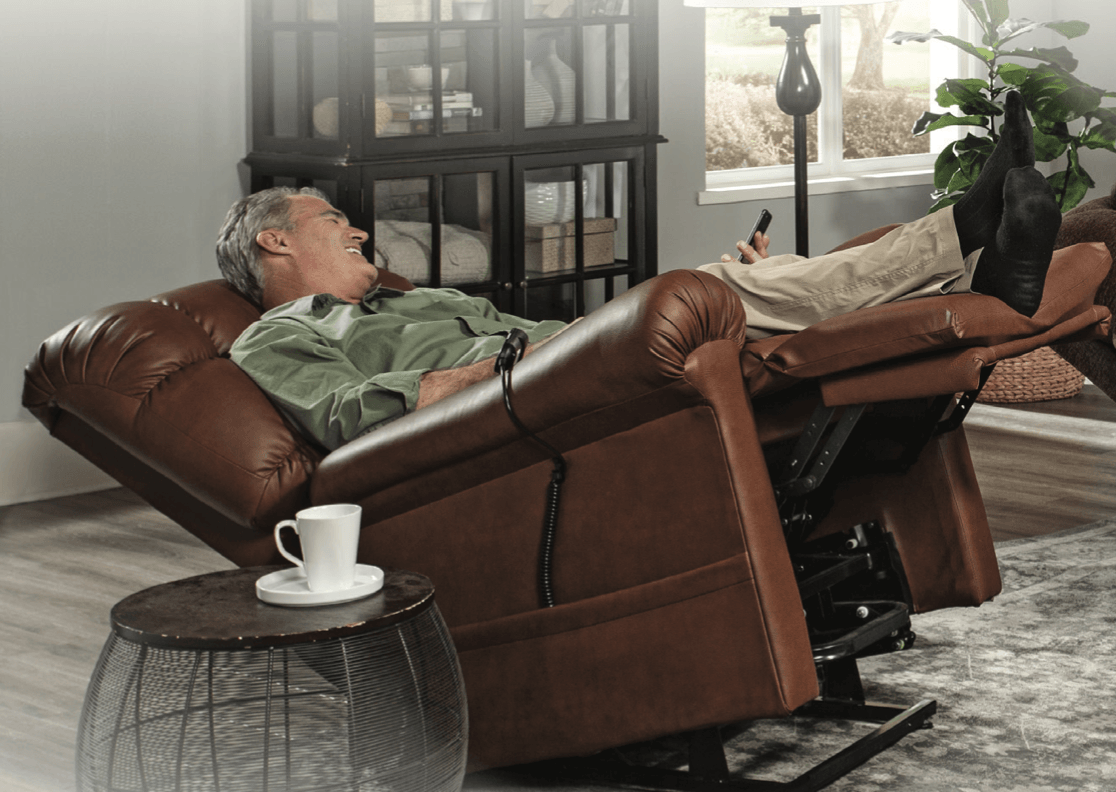 An elderly man is laying in a recliner in a living room.