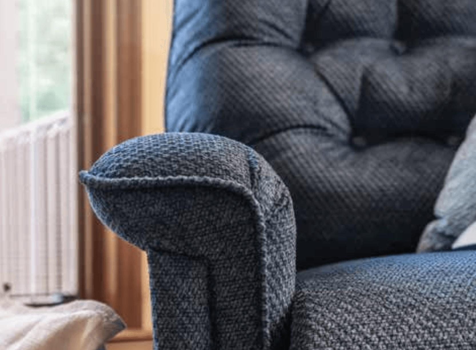 A close up of the arm of a blue recliner in a living room.