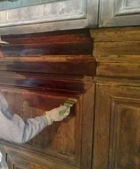 Una persona sta dipingendo un mobile di legno con un pennello.