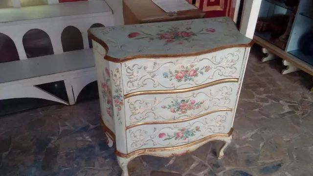 Sul pavimento è appoggiata una piccola cassettiera con dei fiori dipinti sopra.