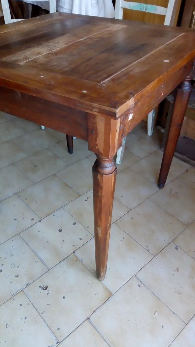 Un tavolo di legno è appoggiato su un pavimento piastrellato.