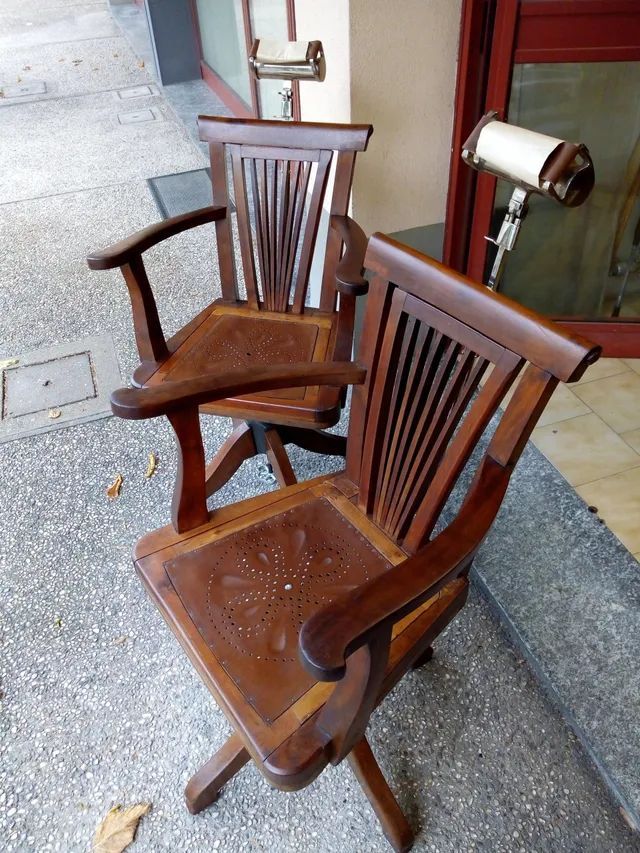 Due sedie di legno sono sedute una accanto all'altra su un marciapiede