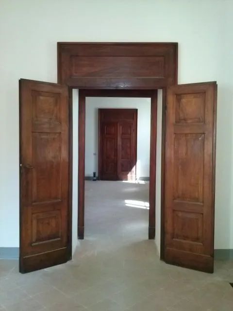 Una stanza con due porte di legno aperte che conducono a una porta.