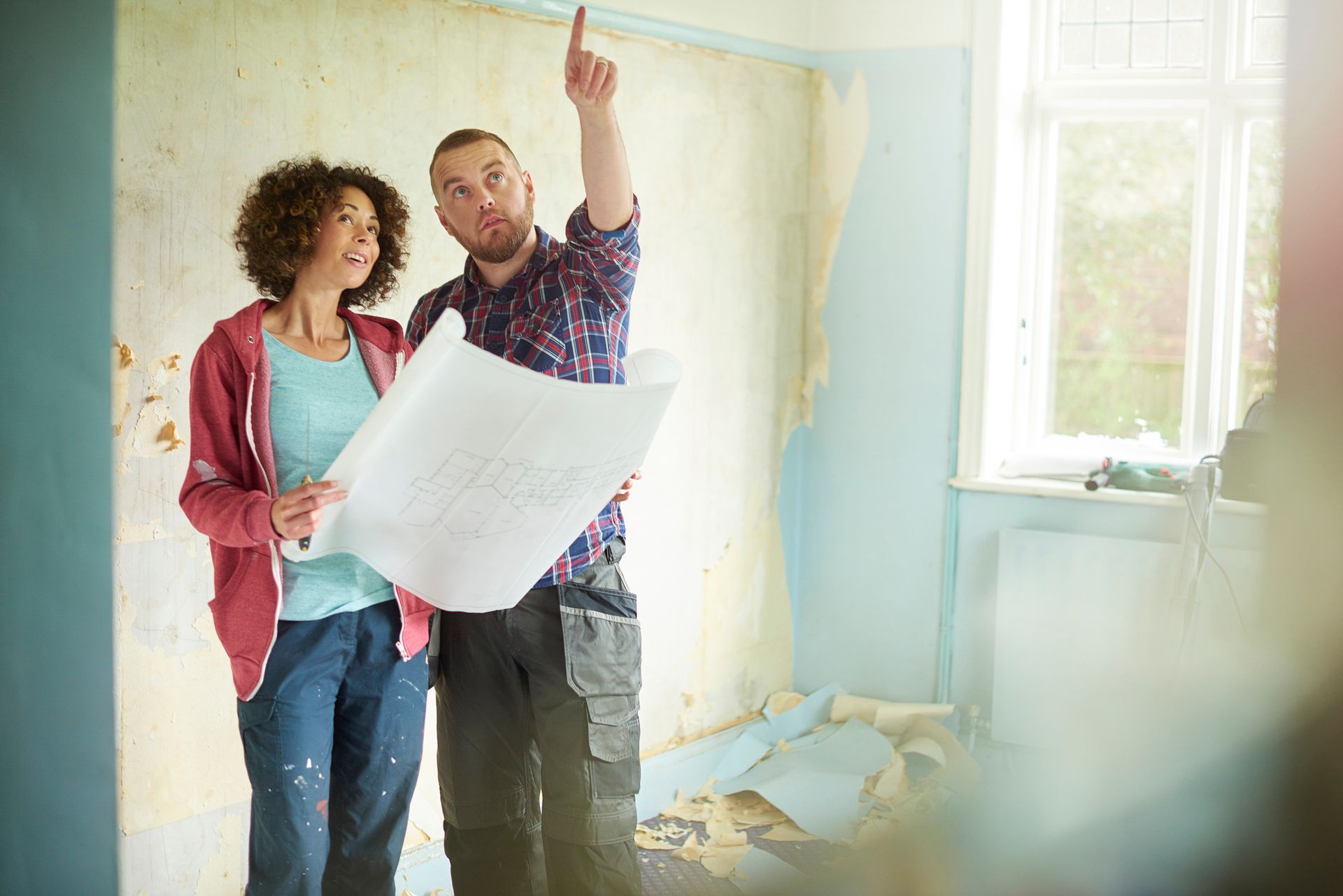A man and a woman are looking at a blueprint in a room. A man and a woman are looking at a blueprint in a room.