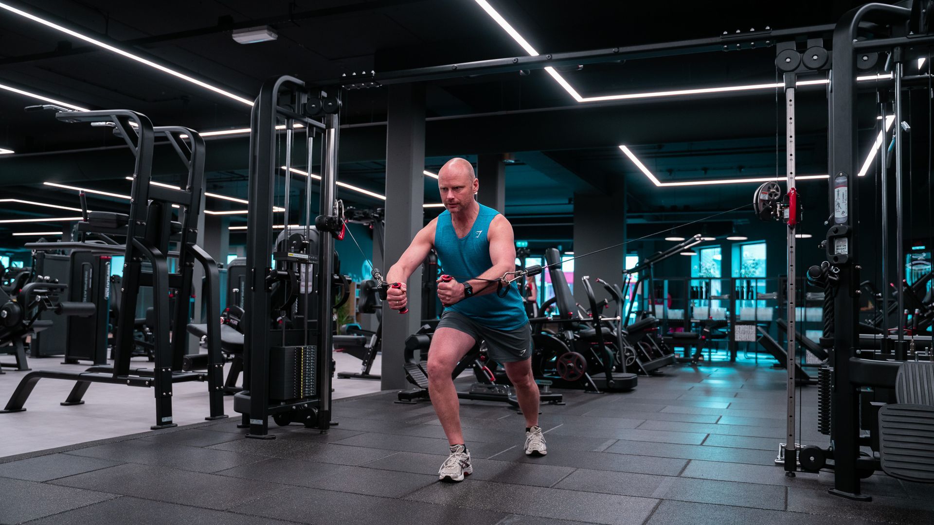 Man in de sportschool, aan het trainen met een kabelmachine, waarbij hij zijn romp draait.